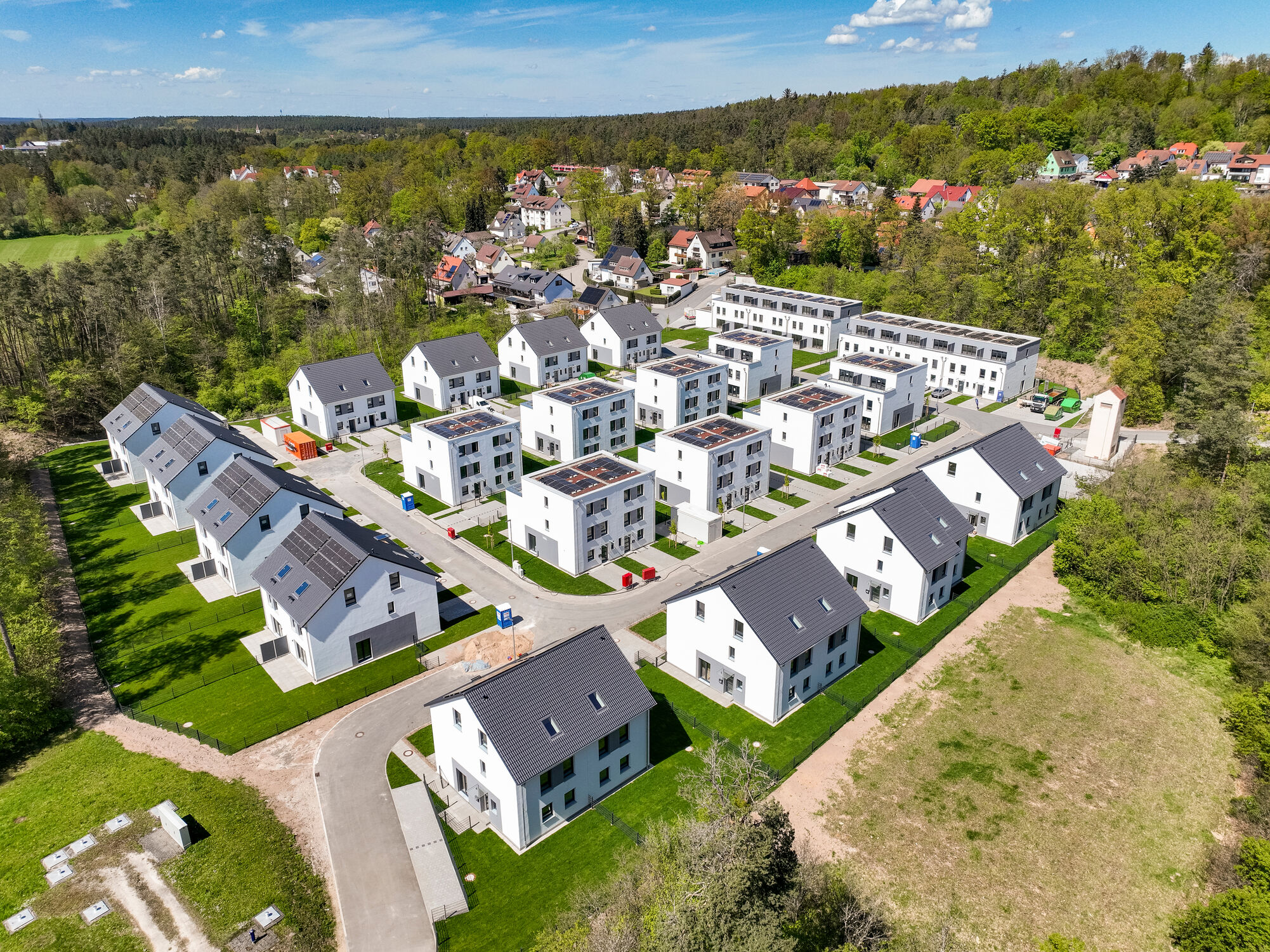 großes Baufeld auf dem viele Reihenhaeuser stehen 